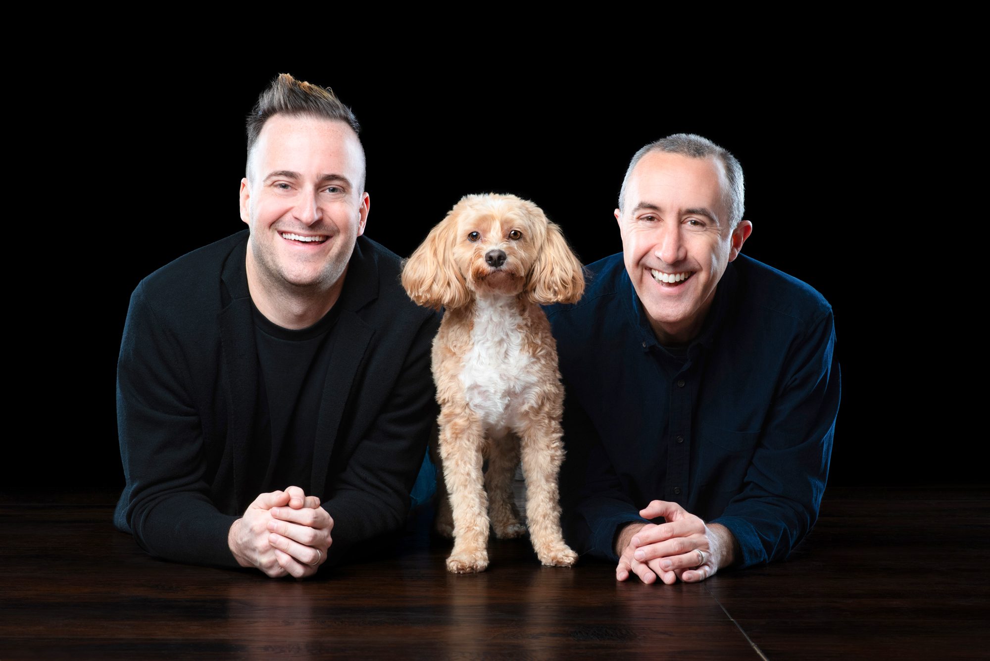 Happy gay couple on black background with mini doodle by chicago pet photographer candice cusic