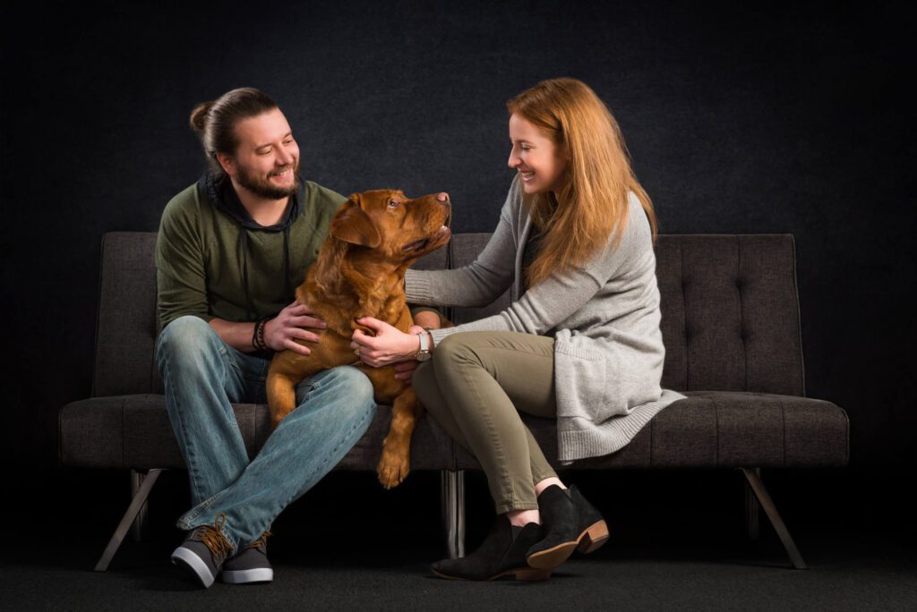 Animal communicator & photographer, Candice C Cusic, and her clients: golden brown large dog with man and woman couple on couch