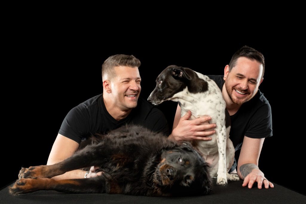 Two dads with their dogs, Britney and Miley, during a family portrait session at a Chicago pet photography studio.
