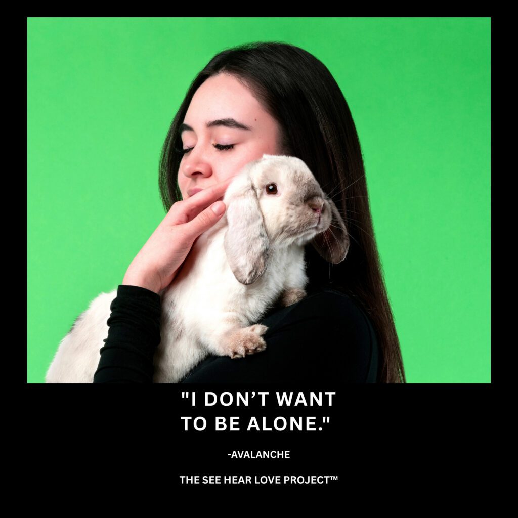 Avalanche, a rescued lop-eared rabbit, held by his caretaker with the quote “I don’t want to be alone.”